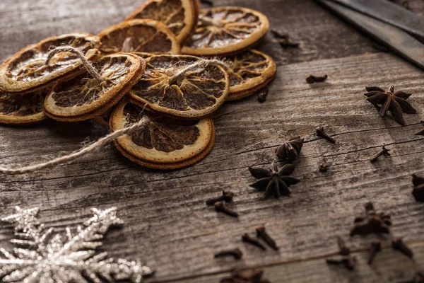 Dried citrus slices on rope near snowflake and anise on wooden surface — Stock Photo