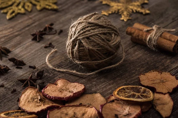 Dried citrus and apple slices near ball of thread on wooden surface — Stock Photo