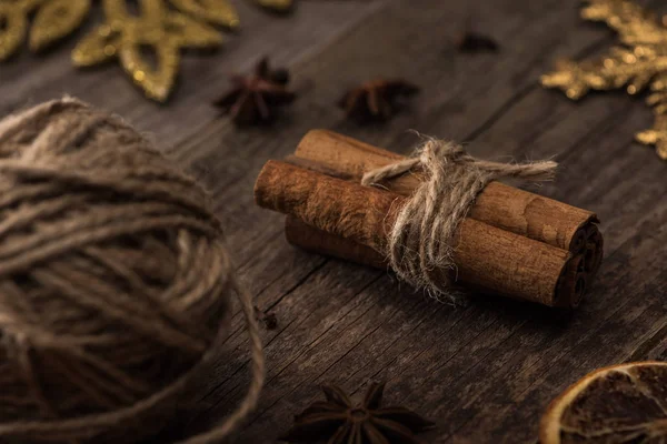Selective focus of ball of thread and cinnamon sticks on wooden surface — Stock Photo