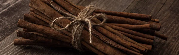 Cinnamon sticks in bunch on wooden rustic table, panoramic shot — Stock Photo