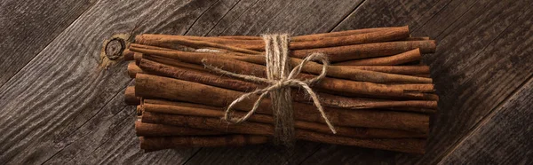 Top view of cinnamon sticks in bunch on wooden rustic table, panoramic shot — Stock Photo