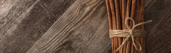 Вид сверху на коричные палочки в связке на деревянном деревенском столе с копировальным пространством, панорамный снимок — стоковое фото