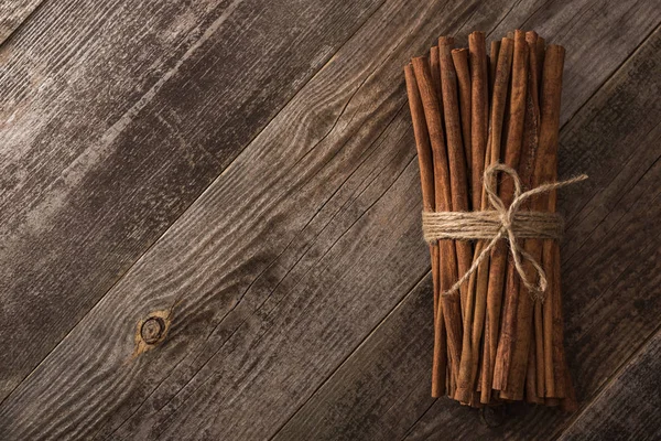 Vue de dessus des bâtons de cannelle en bouquet sur table rustique en bois avec espace de copie — Photo de stock