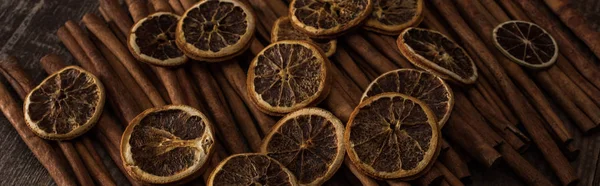 Rodajas de naranja seca y canela sobre fondo de madera, plano panorámico - foto de stock