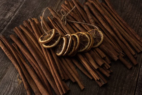 Dried orange slices on thread and cinnamon on wooden background — Stock Photo