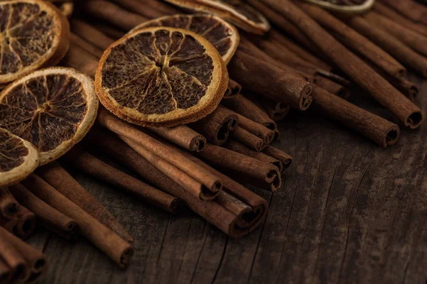 Vue rapprochée des tranches d'orange séchées et de cannelle sur fond en bois — Photo de stock