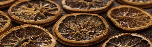 Panoramic shot of dried orange slices on wooden background — Stock Photo