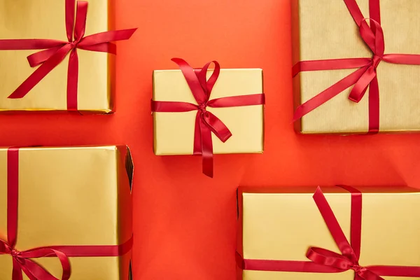 Flat lay with golden gift boxes on red background — Stock Photo