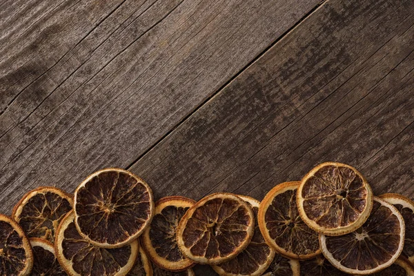Вид сверху на сушеные оранжевые ломтики на деревянном фоне с копировальным пространством — стоковое фото