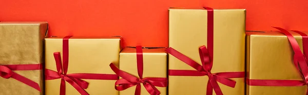Плоский лежал с золотыми подарочными коробками на красном фоне, панорамный снимок — стоковое фото