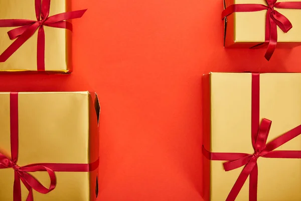 Flat lay with golden gift boxes on red background with copy space — Stock Photo