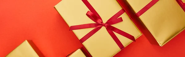 Blick von oben auf goldene Geschenkboxen auf rotem Hintergrund, Panoramaaufnahme — Stockfoto