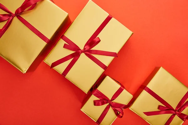 Верхний вид золотых подарочных коробок на красном фоне — стоковое фото