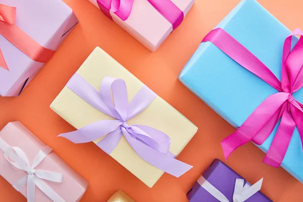 Flat lay with multicolored gift boxes with ribbons and bows on orange background — Stock Photo