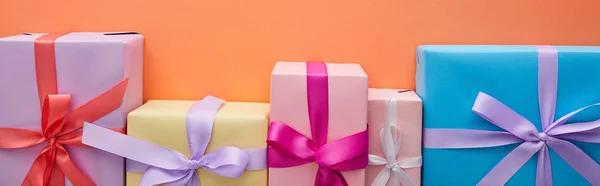 Flat lay with multicolored gift boxes with ribbons and bows on orange background, panoramic shot — Stock Photo