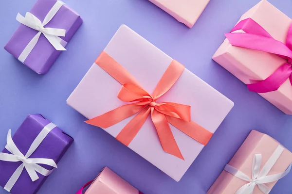 Flache Lage mit bunten Geschenken mit Schleifen auf violettem Hintergrund — Stockfoto