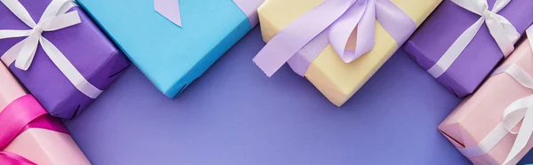 Top view of colorful presents with bows on purple background with copy space, panoramic shot — Stock Photo