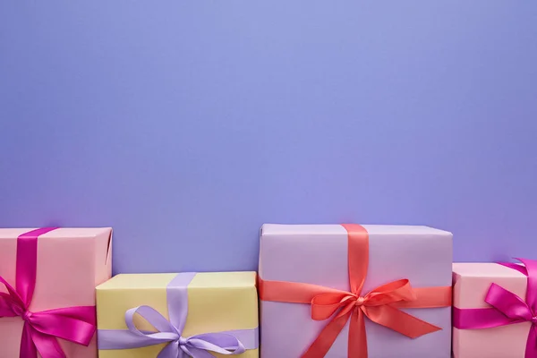 Flat lay with colorful gifts with bows on purple background with copy space — Stock Photo