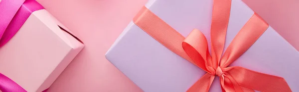 Draufsicht auf bunte Geschenkboxen mit Bändern und Schleifen auf rosa Hintergrund, Panoramaaufnahme — Stockfoto