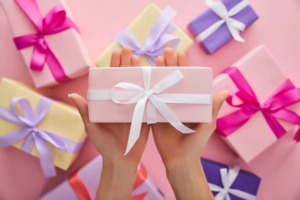 Cropped view of woman holding pink gift above presents — Stock Photo
