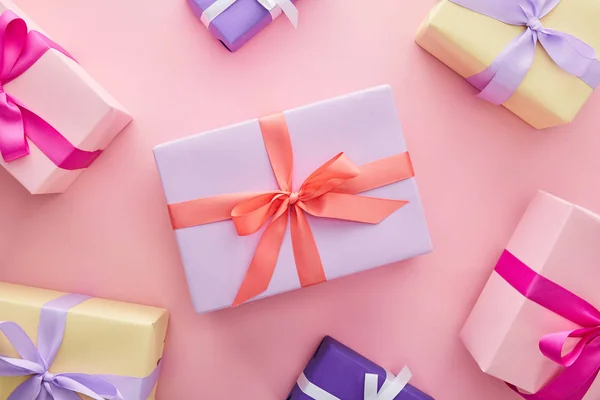 Вид зверху барвисті подарункові коробки зі стрічками та бантами на рожевому фоні — Stock Photo