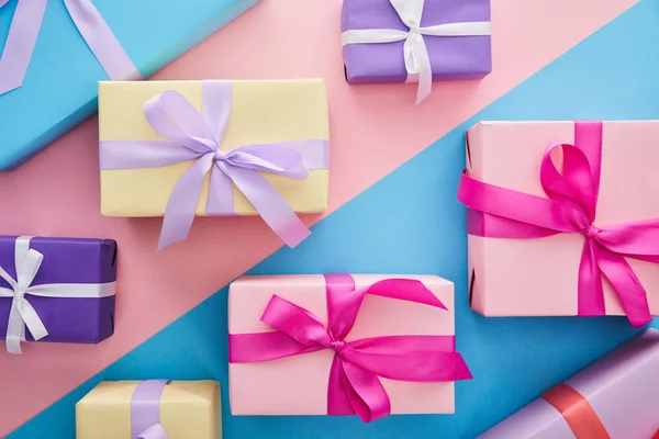 Top view of colorful gift boxes with ribbons and bows on blue and pink background — Stock Photo
