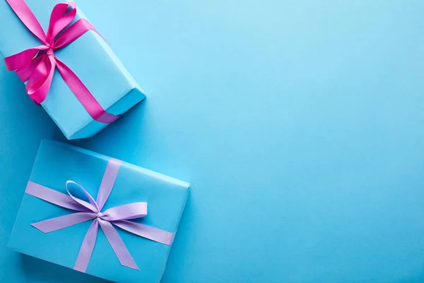 Vista superior de coloridas cajas de regalo sobre fondo azul con espacio de copia - foto de stock