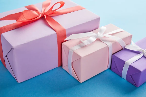 Scatole regalo colorate con nastri e fiocchi su sfondo blu — Foto stock