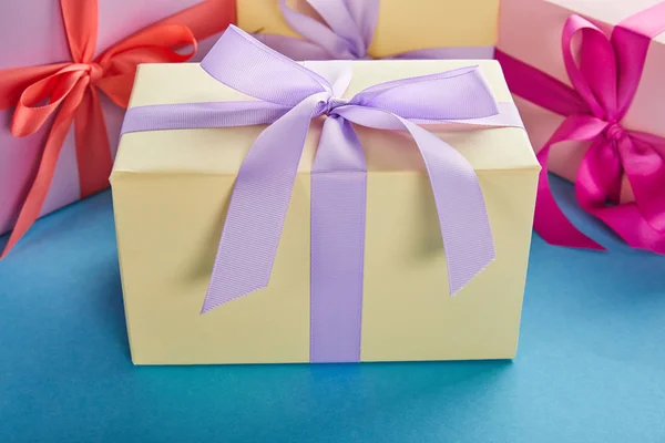 Bunte Geschenkboxen mit Bändern und Schleifen auf blauem Hintergrund — Stockfoto