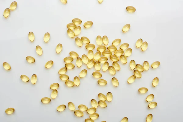 Top view of golden fish oil capsules scattered on white background — Stock Photo