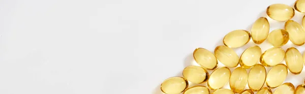 Flat lay with golden fish oil capsules on white background, panoramic shot — Stock Photo