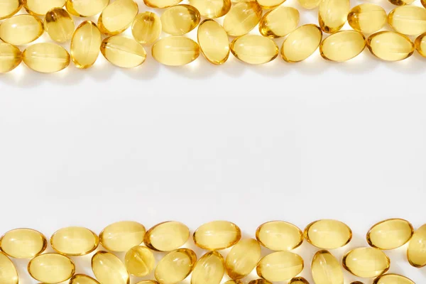 Top view of golden fish oil capsules arranged in frame on white background — Stock Photo