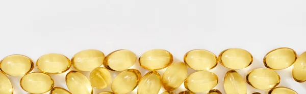 Flat lay with golden fish oil capsules on white background, panoramic shot — Stock Photo