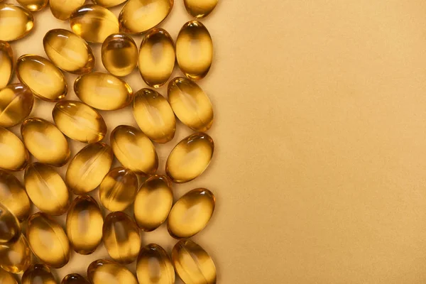 Vista superior de cápsulas de aceite de pescado brillante dorado sobre fondo amarillo con espacio para copiar — Stock Photo