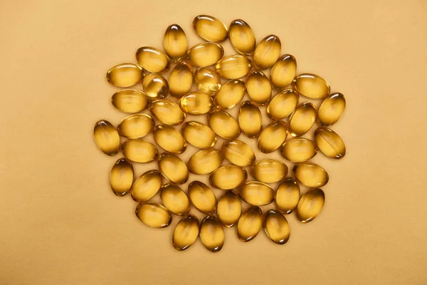 Top view of golden shiny fish oil capsules on yellow background — Stock Photo