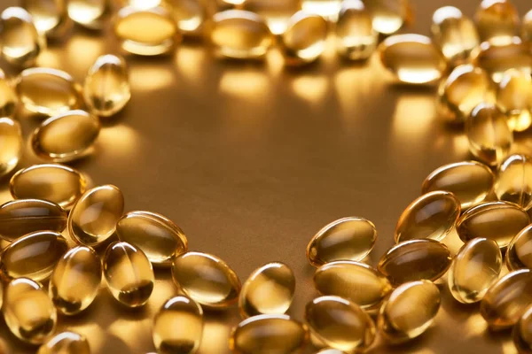 Close up view of shiny fish oil capsules on golden background with copy space — Stock Photo