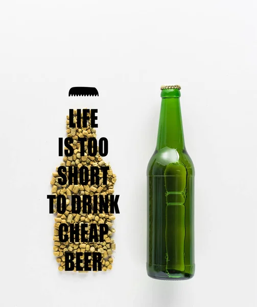 Верхний вид бутылки пива возле нажатого хмеля с жизнью слишком короткий, чтобы пить дешевое пиво буквы изолированы на белом — стоковое фото