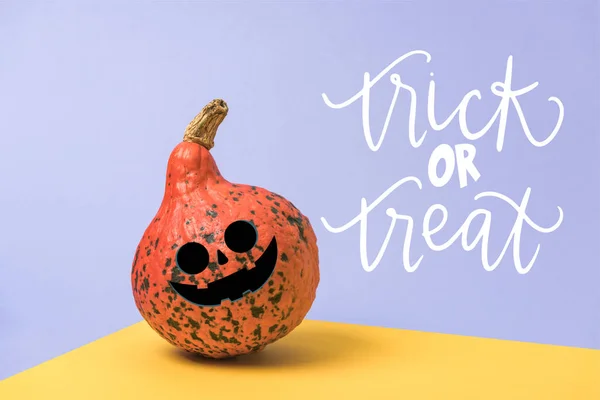 Orange Halloween pumpkin on violet and yellow background with trick or treat lettering — Stock Photo