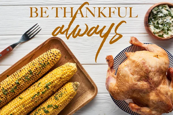 Top view of roasted turkey, apples and grilled corn served on white wooden table with be thankful always illustration — Stock Photo