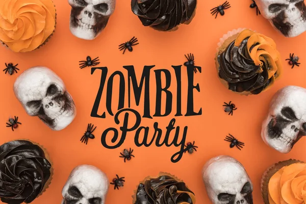 Vista superior de deliciosos cupcakes de Halloween con arañas y calaveras sobre fondo naranja con ilustración de fiesta de zombies - foto de stock