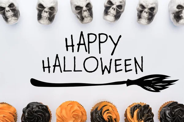 Top view of delicious Halloween cupcakes and skulls on white background  with happy Halloween illustration — Stock Photo