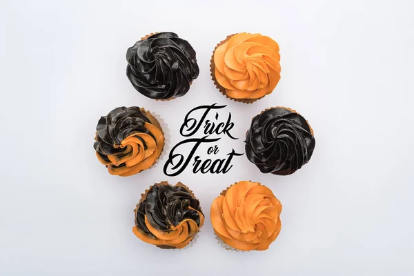Vista superior de deliciosos cupcakes de Halloween en círculo con truco o tratar ilustración aislada en blanco - foto de stock
