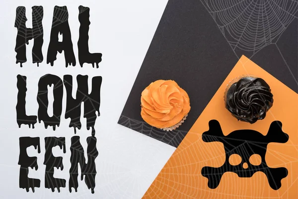 Top view of delicious Halloween cupcakes on black, orange and white background with Halloween illustration — Stock Photo