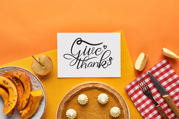 Top view of delicious pumpkin pie near card with give thanks illustration on orange background with apples — Stock Photo