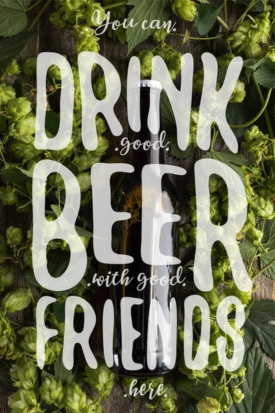 Top view of fresh beer in bottle with green hop on wooden surface with you can drink good beer with good friends here illustration — Stock Photo