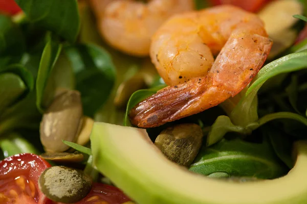 Vista de cerca de la ensalada verde fresca con semillas de calabaza, tomates cherry, camarones y aguacate - foto de stock