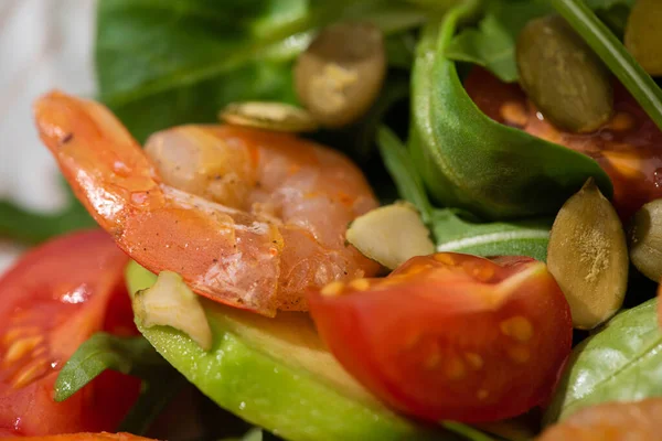 Vista de cerca de la ensalada verde fresca con semillas de calabaza, tomates cherry, camarones y aguacate - foto de stock