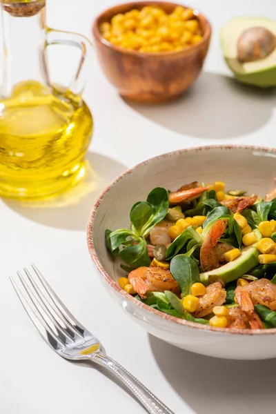 Draufsicht auf frischen grünen Salat mit Garnelen und Avocado auf Teller in der Nähe von Besteck auf weißem Hintergrund — Stockfoto