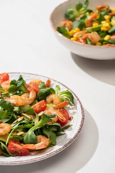 Foco seletivo de salada verde fresca com camarões e abacate em placas em fundo branco — Fotografia de Stock