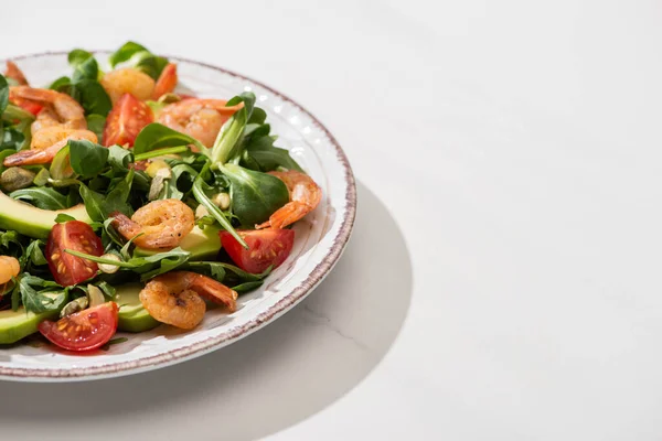 Fresh green salad with shrimps and avocado on plate on white background — Stock Photo